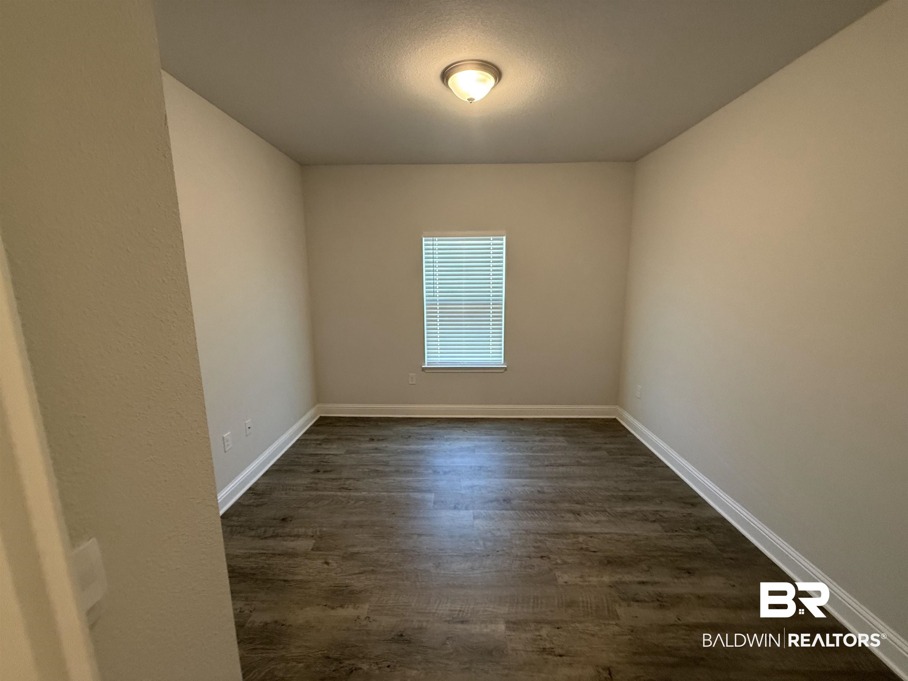 23247 Lieutenant Avenue Foley, AL 36535 - Photo 13 of 47 Neutral wall color with wood-finish flooring and white baseboards