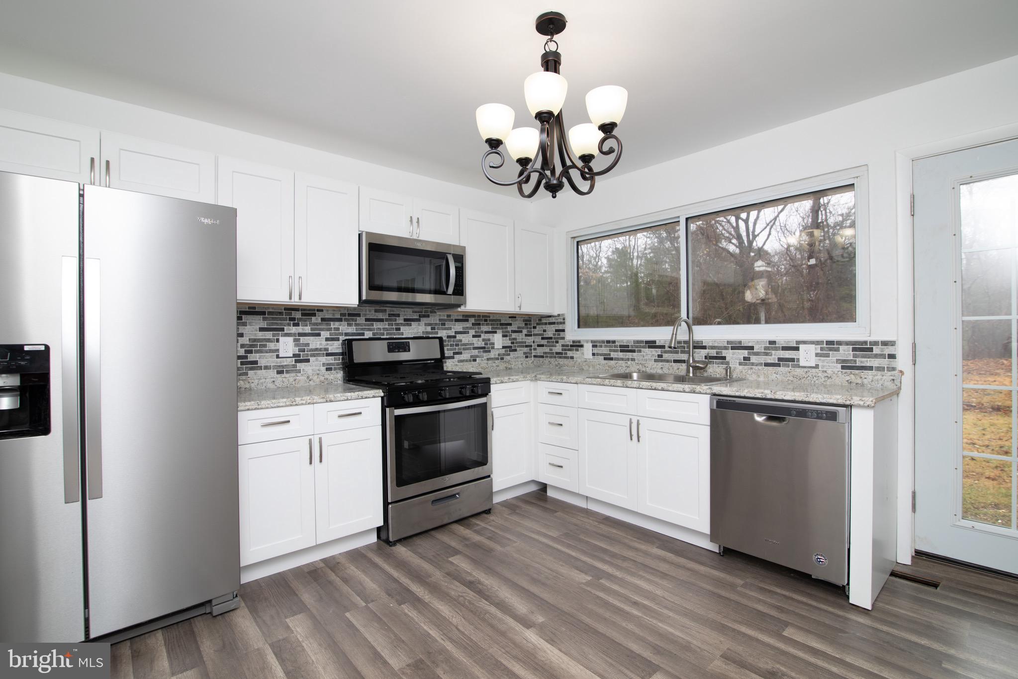 112 Country Club Road Pine Hill, NJ 08021 - Photo 4 of 22 a kitchen with stainless steel appliances granite countertop a refrigerator a stove microwave oven with a dining table and wooden floor