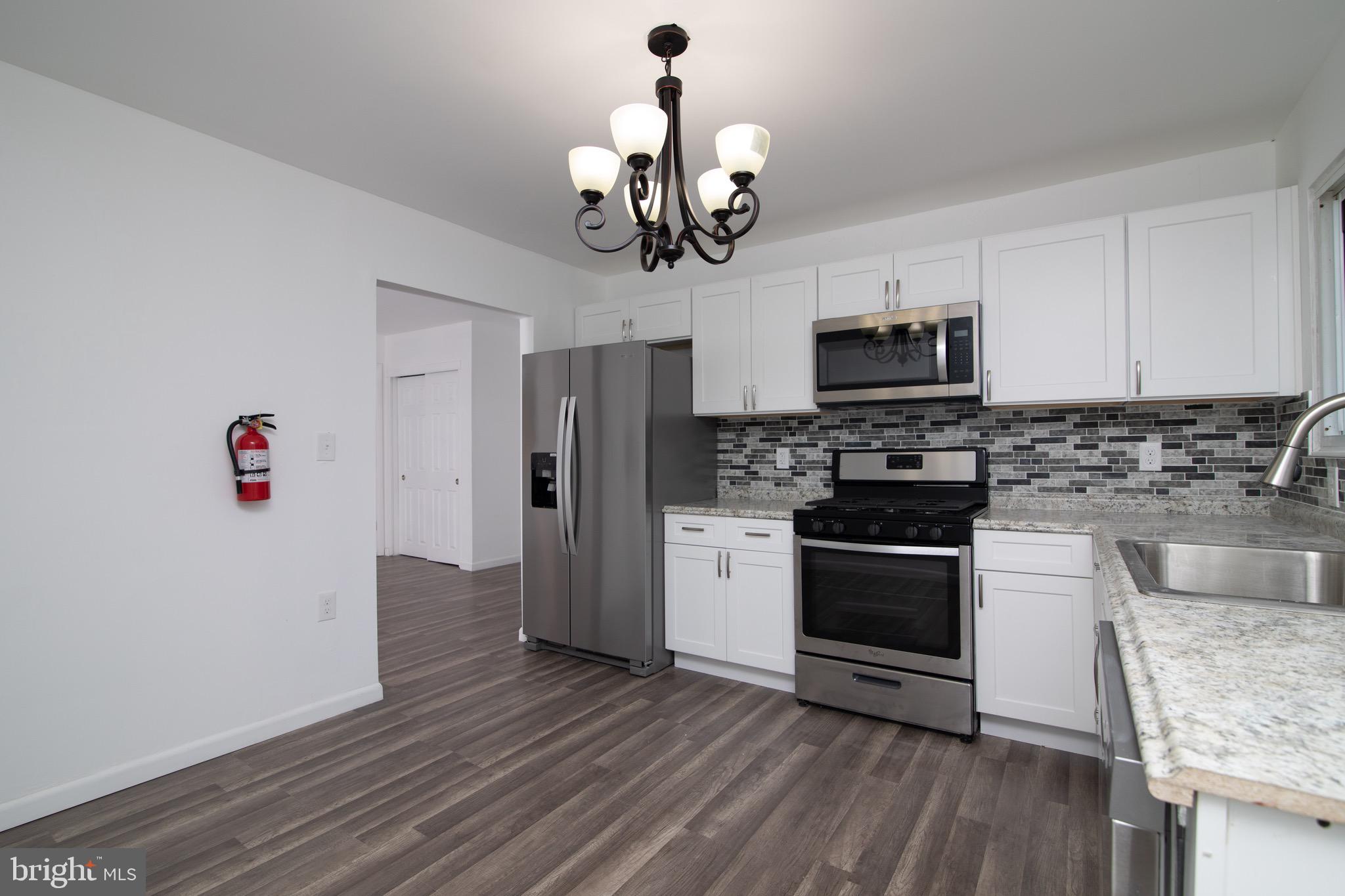112 Country Club Road Pine Hill, NJ 08021 - Photo 6 of 22 a kitchen with stainless steel appliances granite countertop a refrigerator a stove top oven a sink and dishwasher with wooden floor