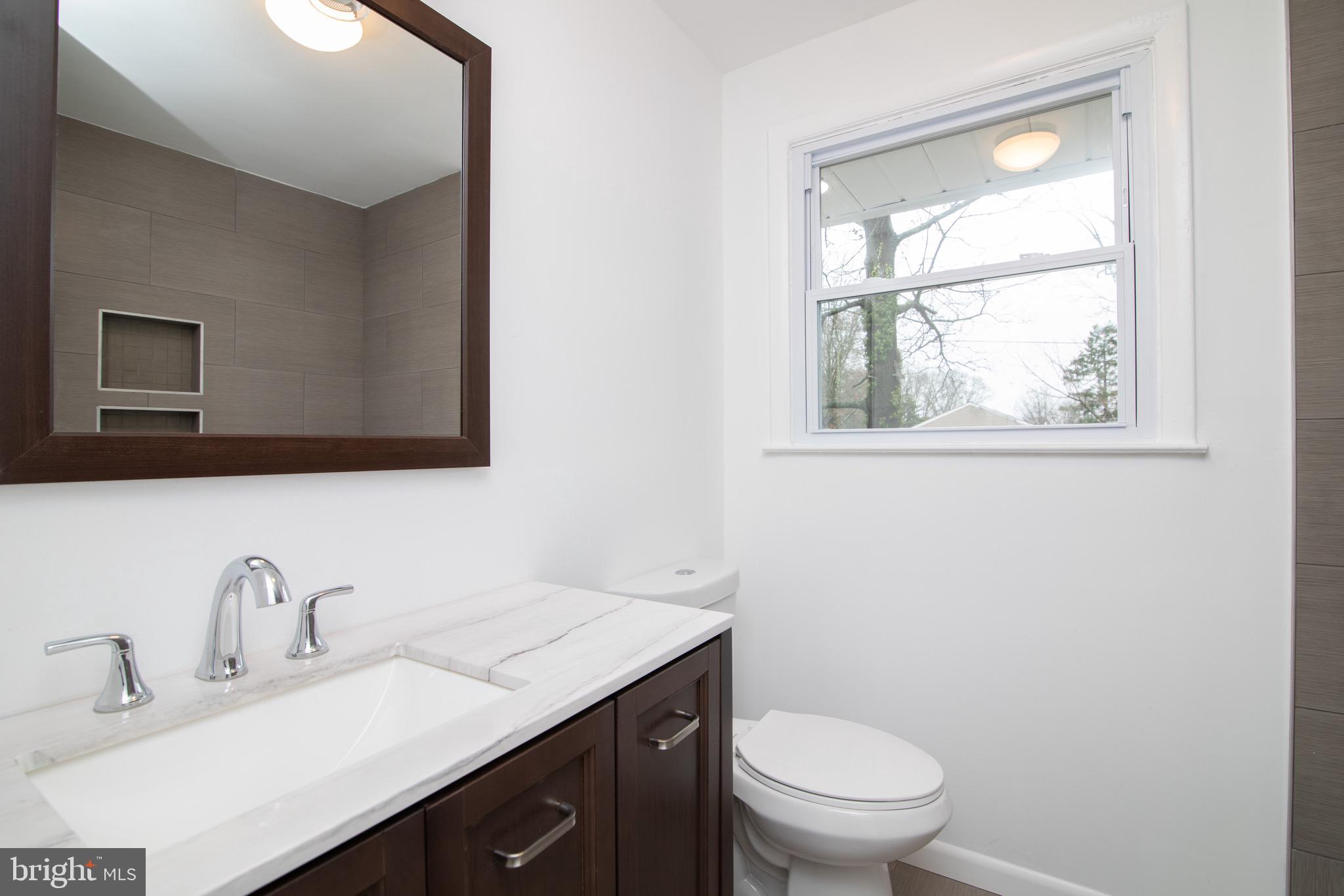 112 Country Club Road Pine Hill, NJ 08021 - Photo 9 of 22 a bathroom with a granite countertop toilet a sink a mirror and a window