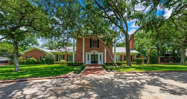 a front view of a house with a yard and trees