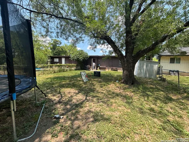 a view of a yard in front of a house with large tree