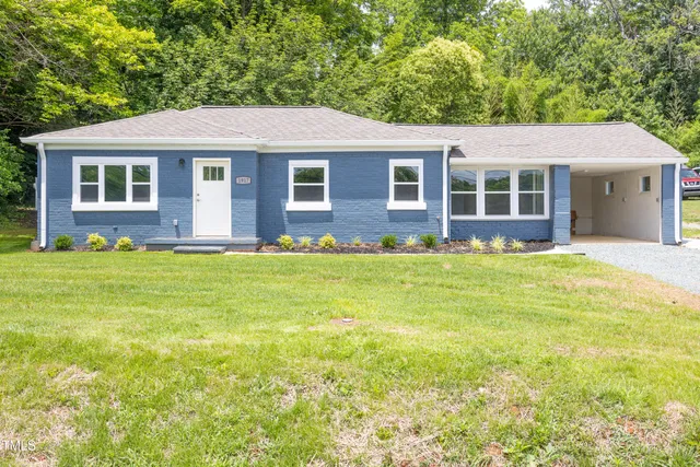 a front view of a house with a garden and trees