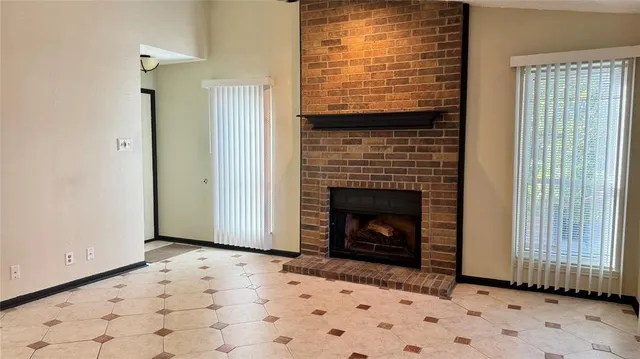a view of an empty room with wooden floor and a fireplace