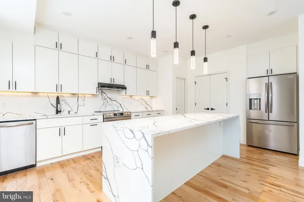a kitchen with kitchen island a sink a stove a refrigerator and white cabinets