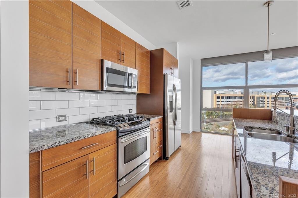 33 North Water Street, Unit 607 Norwalk, CT 06854 - Photo 7 of 40 a kitchen with stainless steel appliances granite countertop a stove a sink and a microwave