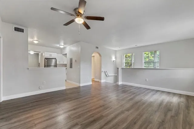 a view of empty room with wooden floor and fan