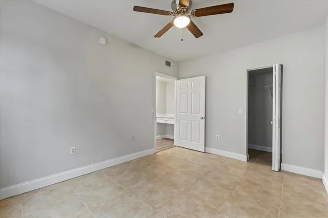 an empty room with closet and a ceiling fan