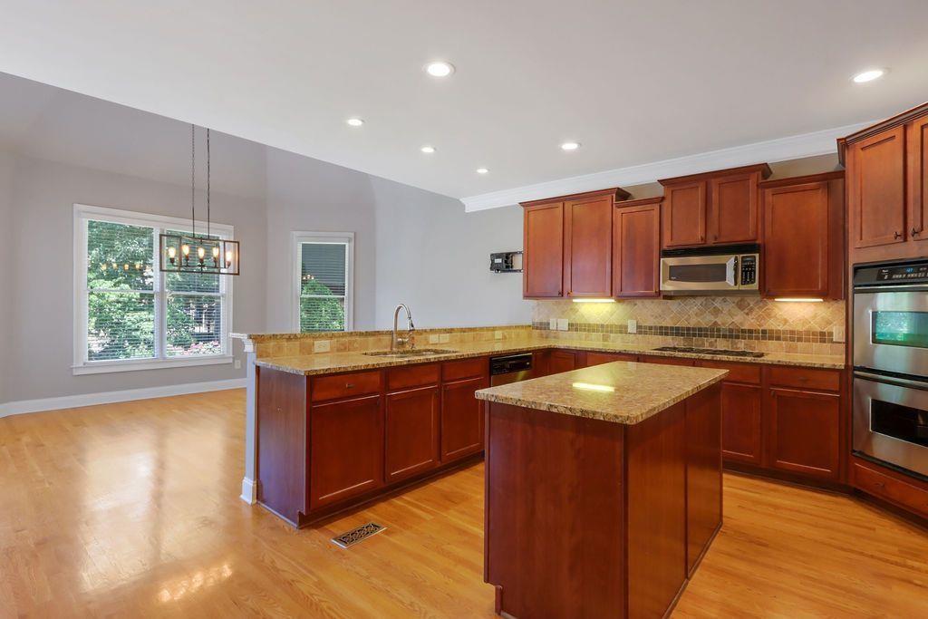 4174 Highglen Trace Northeast Dacula, GA 30019 - Photo 19 of 48 a kitchen with stainless steel appliances granite countertop wooden cabinets a sink and a stove