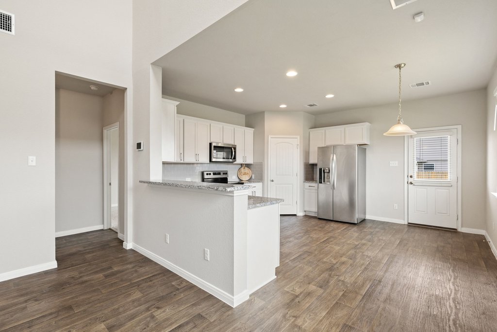 102 Ashford Way Georgetown, TX 78626 - Photo 8 of 28 A well-appointed kitchen features stainless steel appliances, granite counters, and wood flooring throughout the open-concept space.