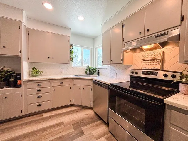 a kitchen with stainless steel appliances granite countertop a stove a sink and a refrigerator