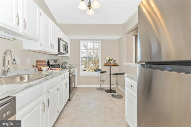 a kitchen with stainless steel appliances granite countertop a stove a sink and a white cabinets