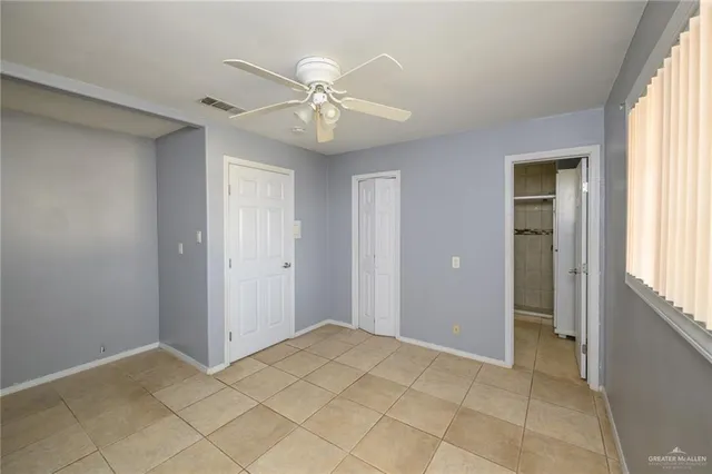 a view of an empty room with window and chandelier fan