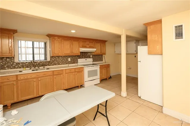 a kitchen with stainless steel appliances a sink a stove a refrigerator cabinets and a window