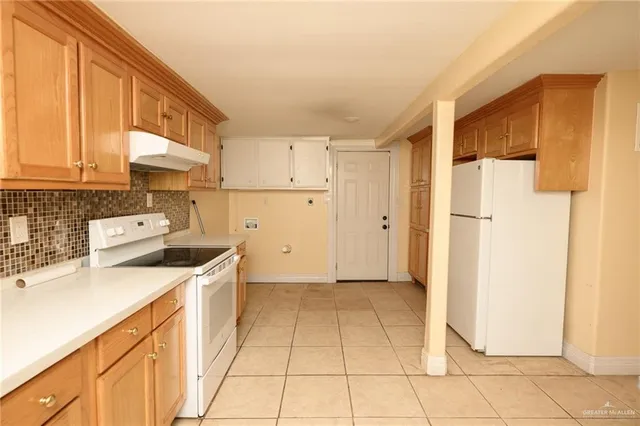 a kitchen with a refrigerator a stove top oven and cabinets