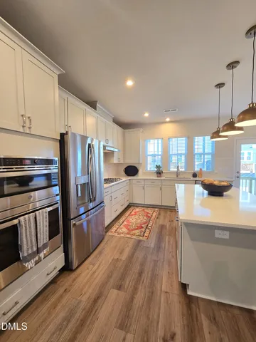 a large kitchen with stainless steel appliances and wooden floor