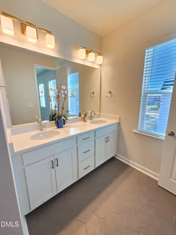 a spacious bathroom with a double vanity sink a large mirror and a