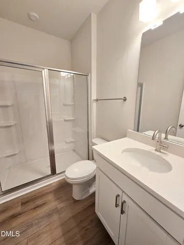 a bathroom with a sink a toilet a mirror and shower