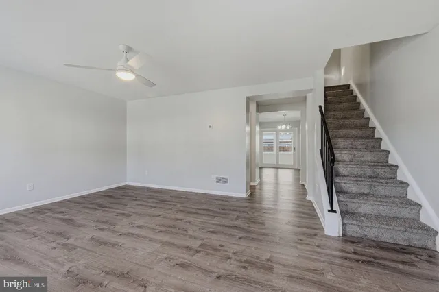 a view of an empty room with wooden floor and stairs