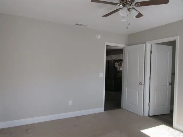 an empty room with windows and fan