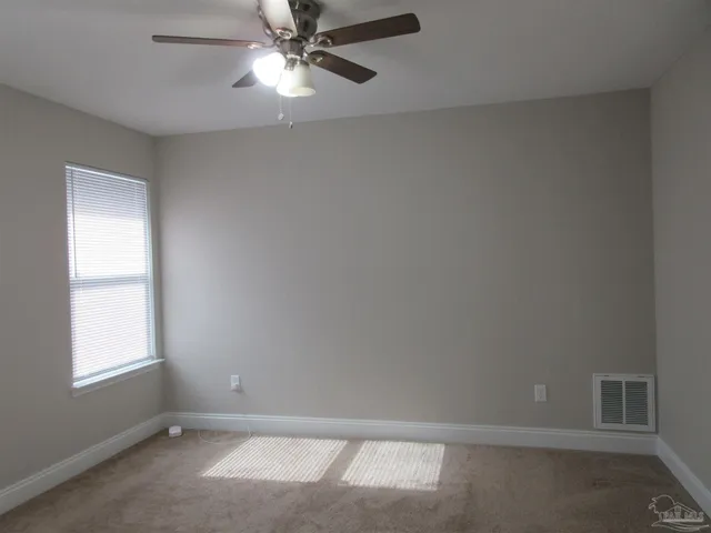an empty room with a window and a fan