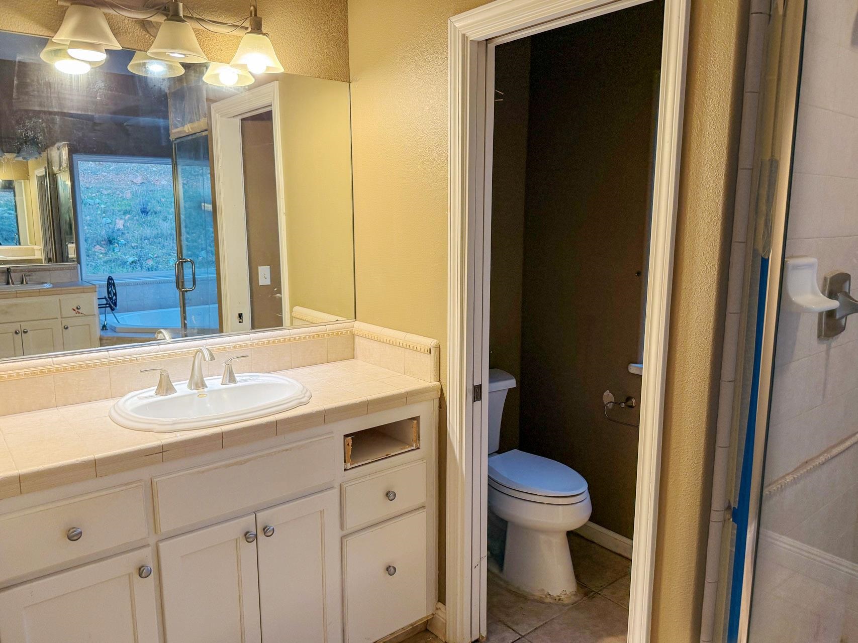 16446 Stamp Mill Loop Road East Jamestown, CA 95327 - Photo 16 of 32 a bathroom with a granite countertop toilet a sink and a mirror