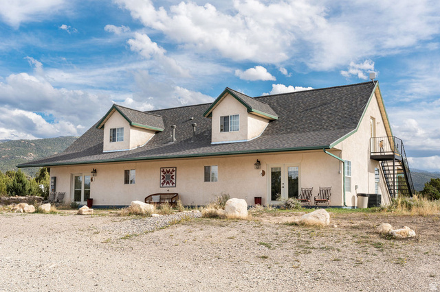 11550 Pigeon Hollow Road Spring City, UT 84662 - Photo 45 of 85 Stucco exterior with dormer windows, dark asphalt shingle roof, and a visible exterior staircase