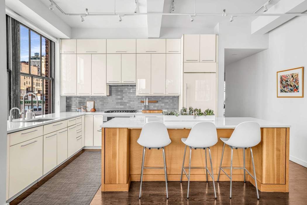 11 West 30th Street, Unit 14 Manhattan, NY 10001 - Photo 7 of 18 a kitchen with a dining table chairs and white cabinets