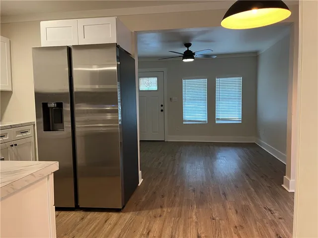 an empty room with wooden floor cabinet and windows