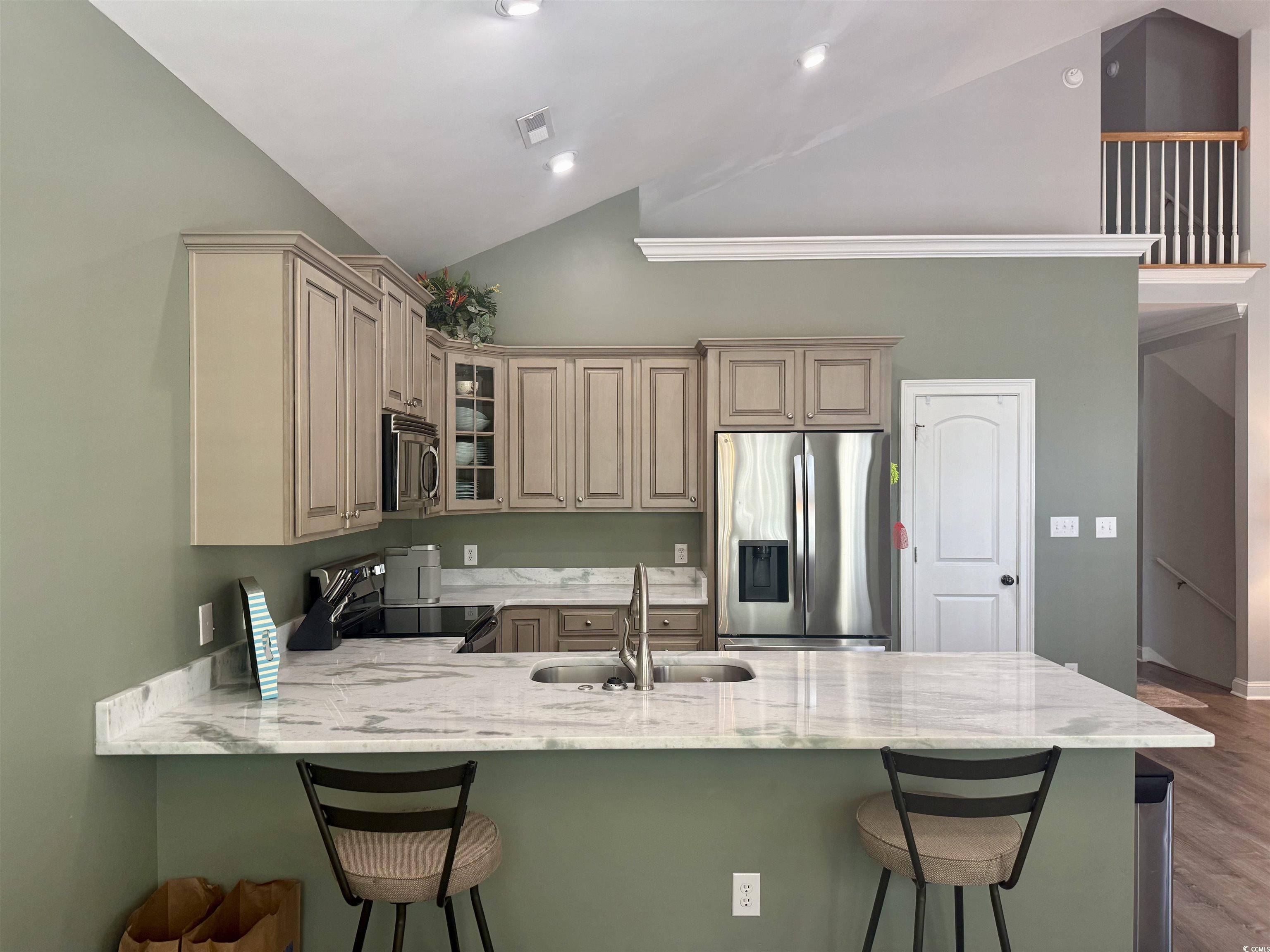 118 Georges Bay Road Murrells Inlet, SC 29576 - Photo 3 of 39 Kitchen featuring stainless steel appliances, a breakfast bar, a peninsula, light stone countertops, and high vaulted ceiling