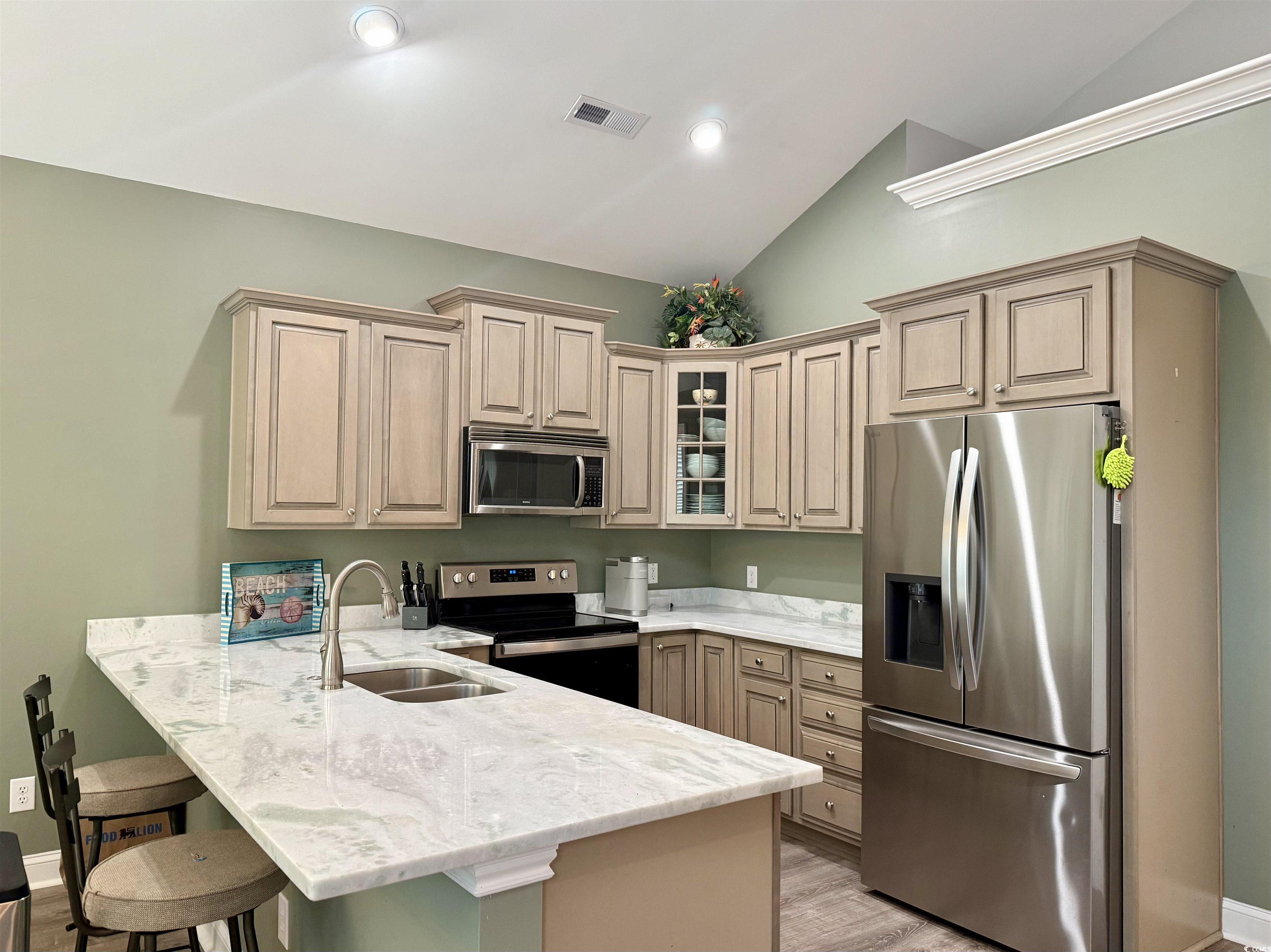 118 Georges Bay Road Murrells Inlet, SC 29576 - Photo 4 of 39 Kitchen with appliances with stainless steel finishes, vaulted ceiling, a kitchen bar, light stone counters, and light wood-type flooring
