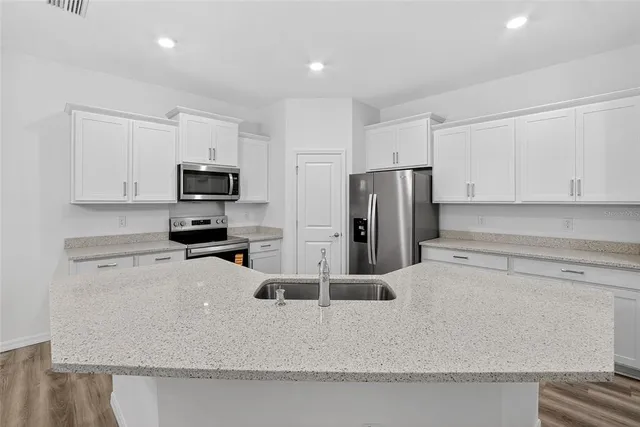 a kitchen with kitchen island a sink stainless steel appliances and cabinets