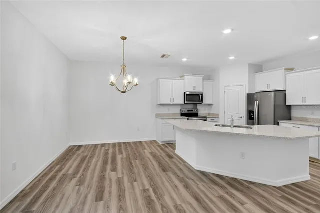 a kitchen with kitchen island a counter top space a sink stainless steel appliances and cabinets
