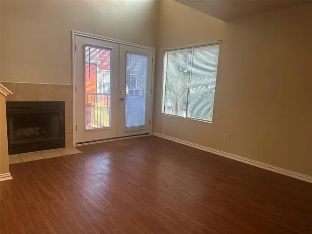 an empty room with wooden floor fireplace and windows