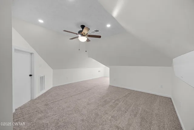 a view of an empty room with a chandelier fan