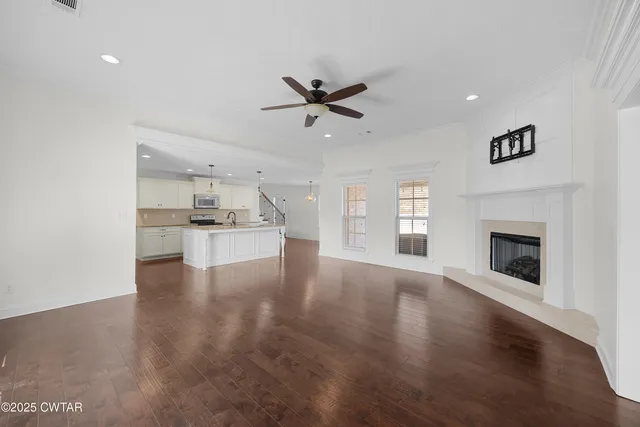 a view of an empty room with kitchen and fireplace