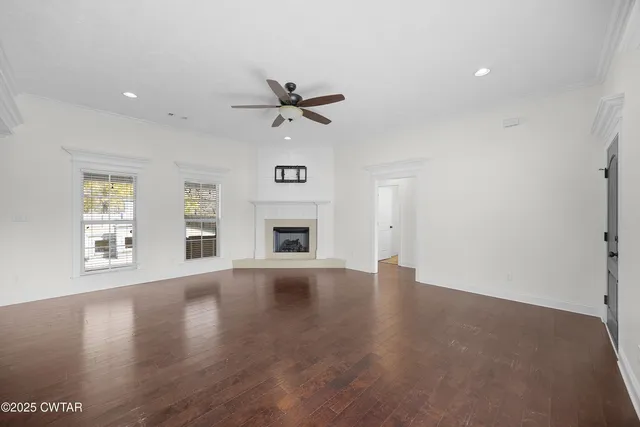 a view of an empty room with a window and wooden floor