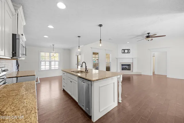 a large kitchen with granite countertop a sink a stove and a wooden floors