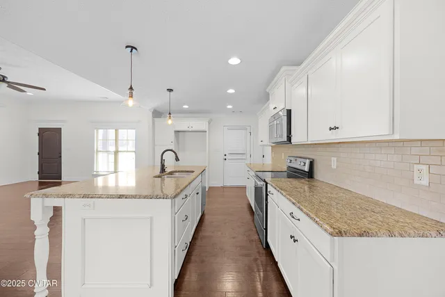 a kitchen with granite countertop a sink a counter space appliances and cabinets
