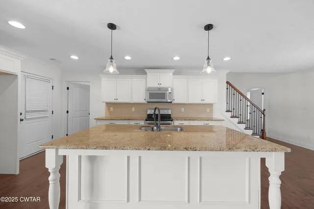 a kitchen with kitchen island granite countertop a sink a center island and cabinets
