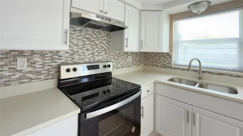 a kitchen with stainless steel appliances a refrigerator a stove and white cabinets