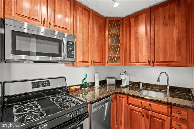 a kitchen with stainless steel appliances granite countertop a stove a sink dishwasher and microwave oven with granite countertops