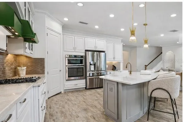 a kitchen with stainless steel appliances kitchen island granite countertop a stove a sink a refrigerator and a refrigerator