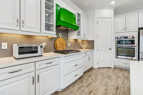 a kitchen with granite countertop white cabinets stainless steel appliances and a wooden floor