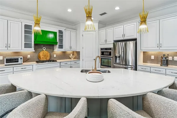 a kitchen with stainless steel appliances kitchen island granite countertop a table chairs stove and refrigerator
