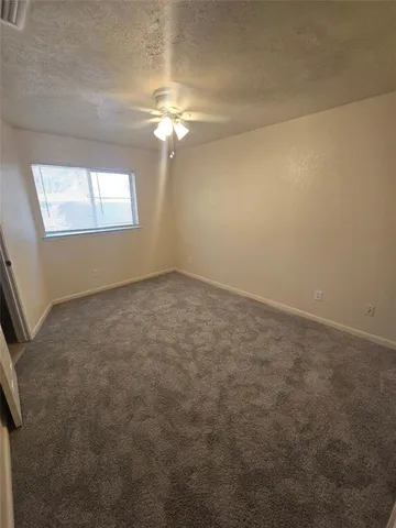 an empty room with a chandelier fan and windows