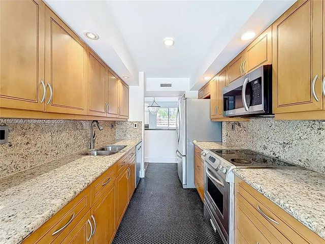 a kitchen with stainless steel appliances granite countertop a stove a sink and a microwave