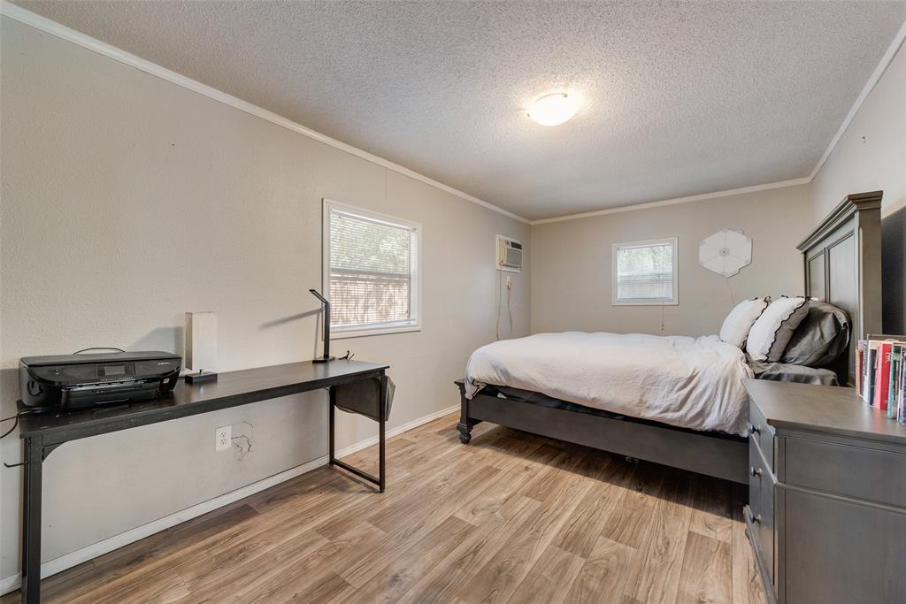 233 East High Street Wills Point, TX 75169 - Photo 30 of 40 Bedroom featuring a textured ceiling, light wood-type flooring, multiple windows, and ornamental molding