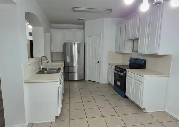 a kitchen with a sink a stove top oven and refrigerator