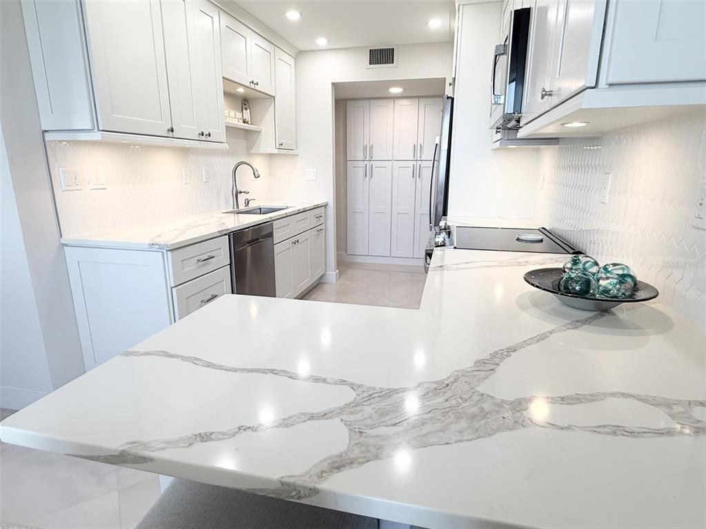 1050 Longboat Club Road, Unit 803 Longboat Key, FL 34228 - Photo 14 of 39 a kitchen with stainless steel appliances kitchen island granite countertop a sink a stove and white cabinets